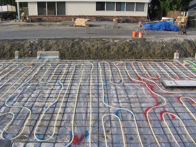 Installation of radiant floor PEX tubing. PEX tubing is installed around in-ground lift to accommodate above-ground lift base plate.